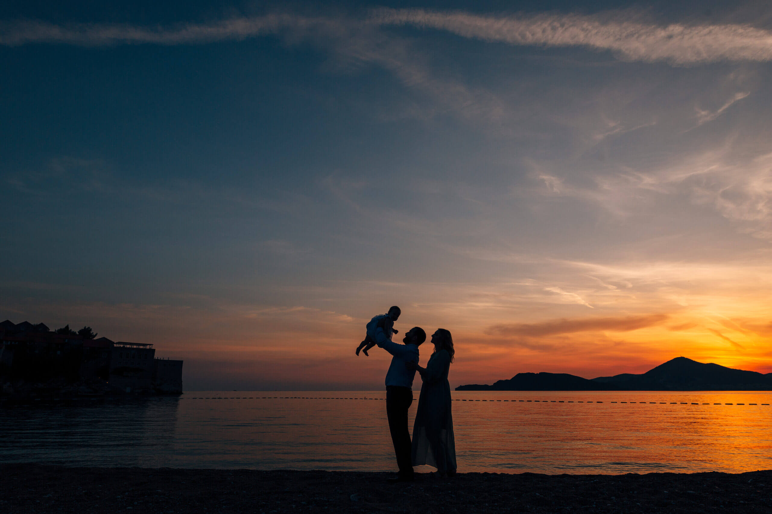 Sunset over water with family silhouette